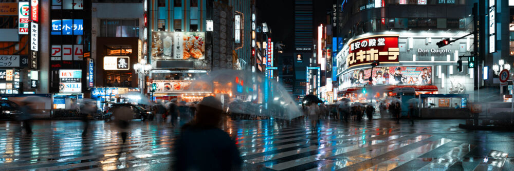 Panorama of a Shinjuku street crossing on a rainy night in Tokyo, Japan