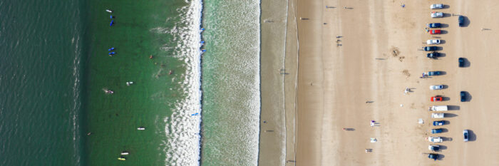Aerial of surfers riding a wave at inch beach in Ireland