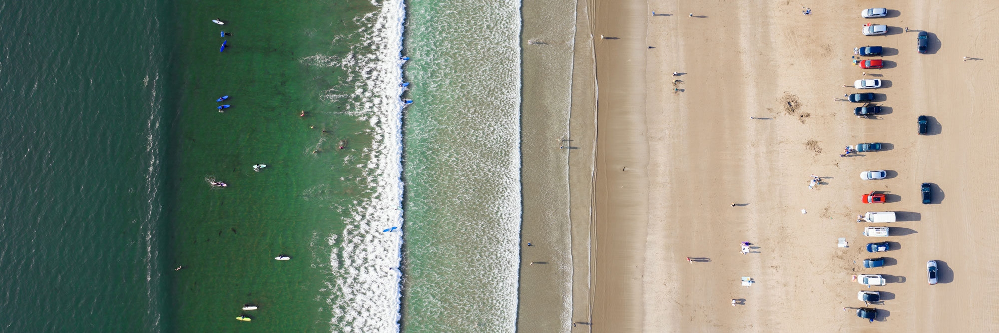 Aerial of surfers riding a wave at inch beach in Ireland