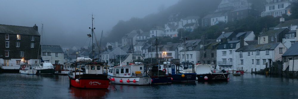 Panorama of Polperro Harbour and fishing boats during morning mist along the south west coast path in Cornwall