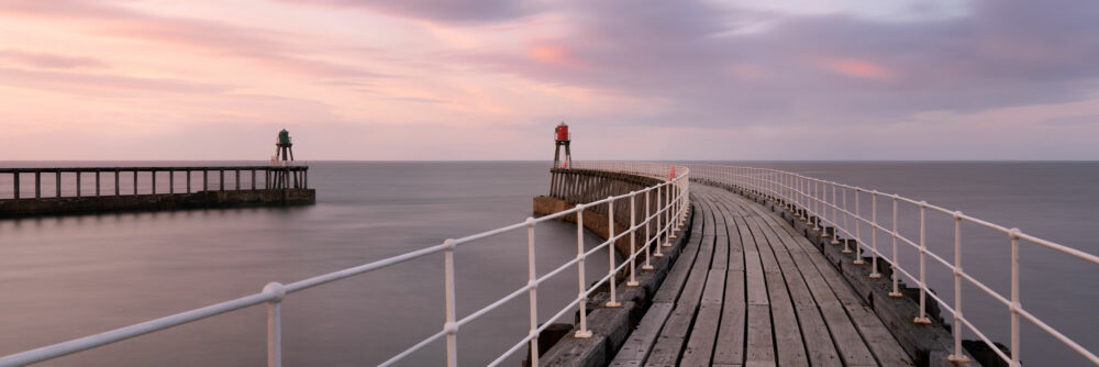 Panorama of Whitby pier lighthouses and harbour at sunset