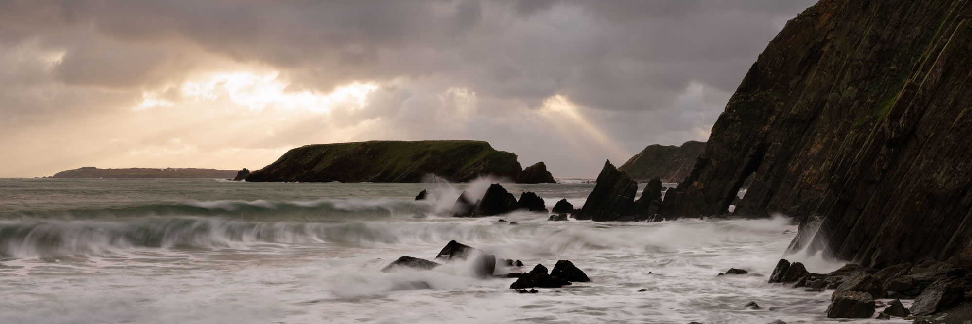 Panorama of Mrloes Sands during a storm as the sun bursts through the clouds