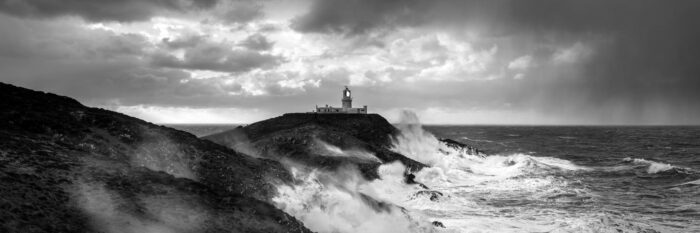 Stumble head lighthouse in a winter storm as waves crash against the rugged coastline
