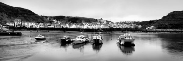 Panorama of Staithes fishing boats and village and low tide black and white