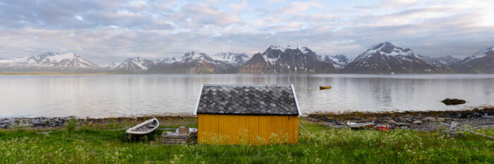 Panorama of a yellow Norwegian hut with the lunges fjord and alps behind in Norway