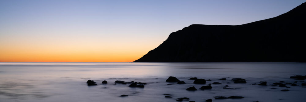 Panorama of the sunset glow at midnight behind Hustinden mountain on Flakstadoya in the Lofoten Islands