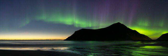 Panorama of the Aurora Borealis over a beach in the Lofoten Islands in the arctic circle