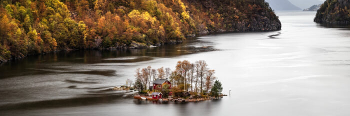 Panorama of a red Norwegian cabin on an island in Lovrafjorden in Autumn in Norway