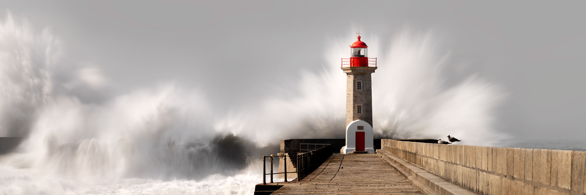 Panorama of a lighthouse in Portugal as waves crash over it