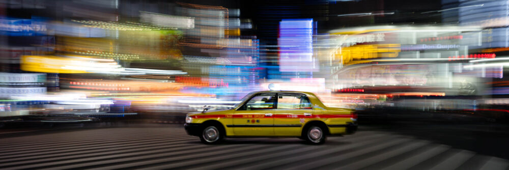 Panorama of a Yellow Toyota Comfort Taxi rushing through Shinjuku at night in Tokyo Japan